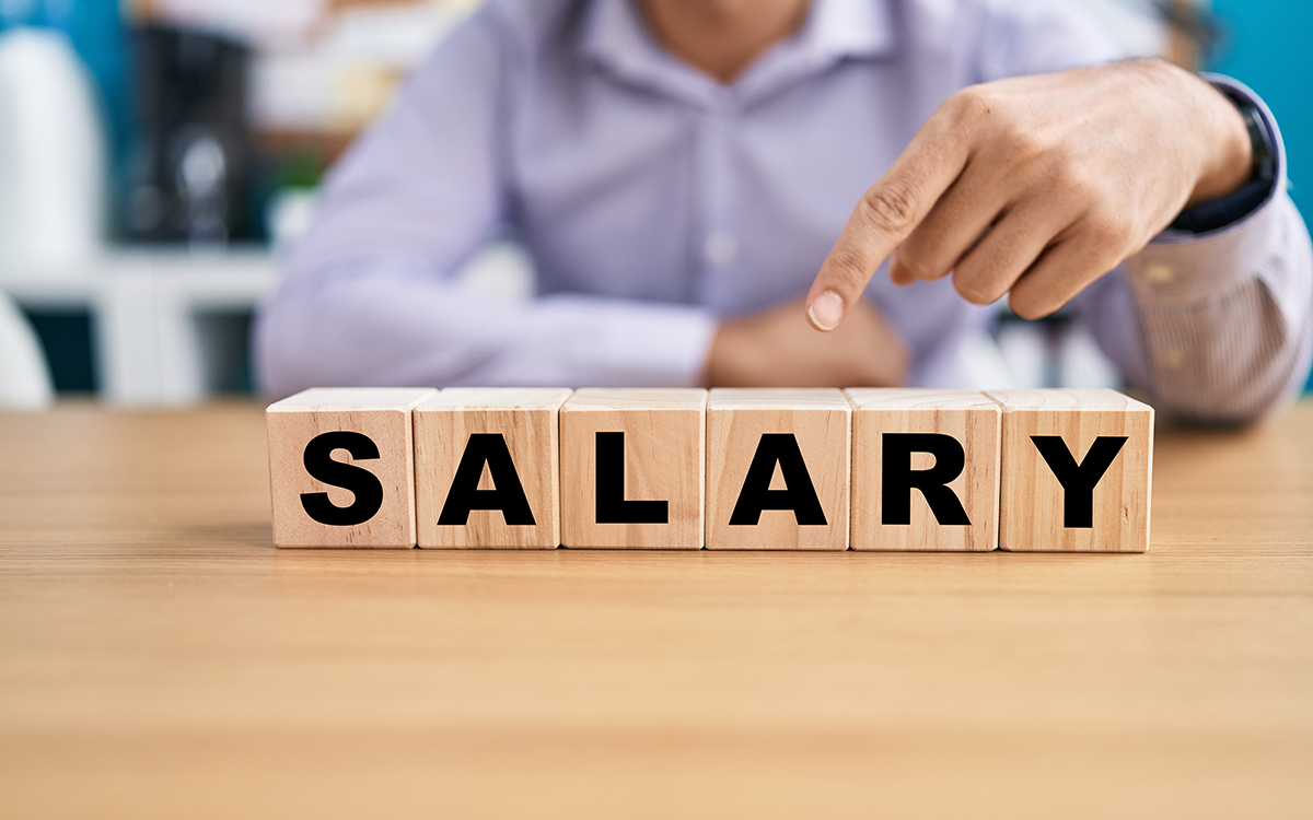 Young man holding cubes with salary word on the table